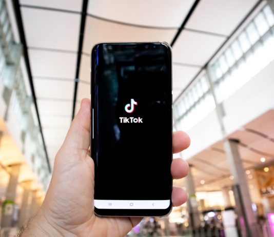 Tik Tok Owner to Expand Into AI Chip Production Man holding a smartphone with TikTok on it